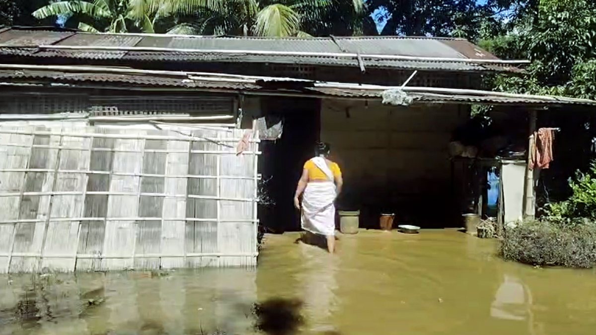 Woman wades through floodwaters inside her home in Jorhat