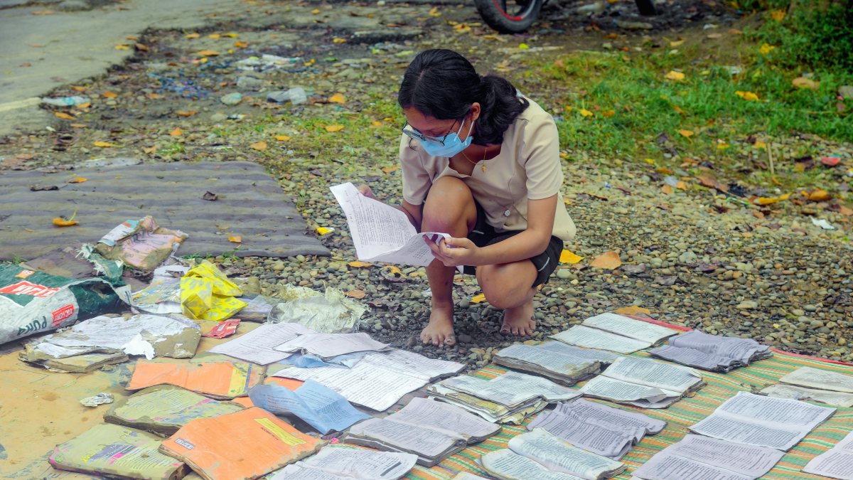 Assam girl dries flood-soaked textbooks in Sivasagar