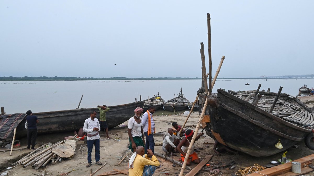 Boatmen repair wooden boats on Ganga riverbank in Patna