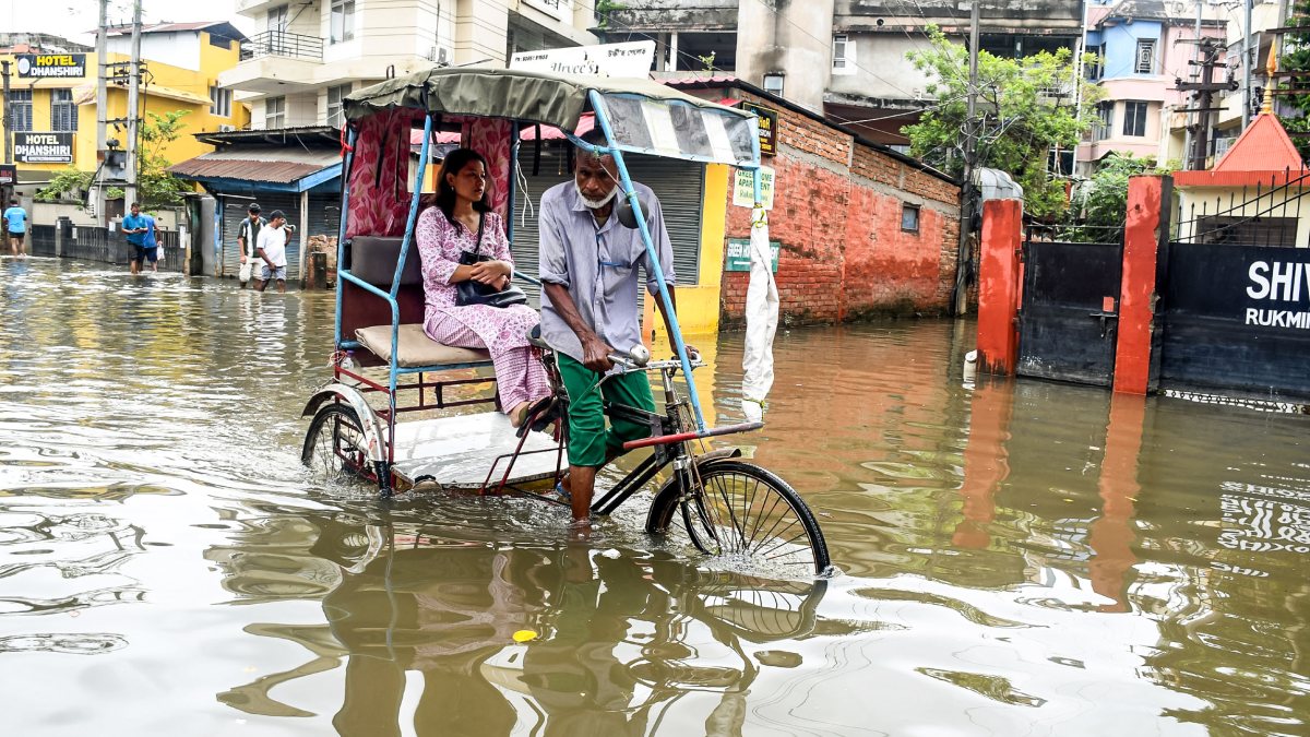 Rickshaw puller wades through waterlogged Guwahati street after heavy rain