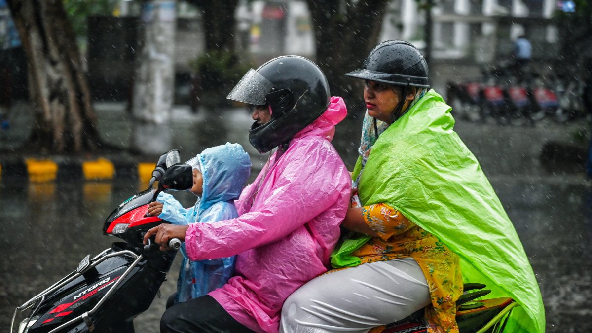 Heavy rain drenches Delhi, family rides scooter in raincoats