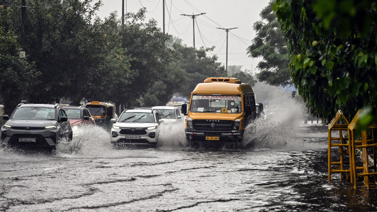 Delhi commuters wade through waterlogged road after heavy rain