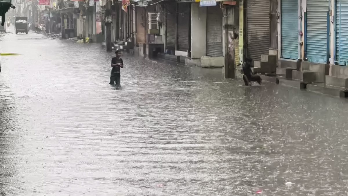 Child wades through flooded market street after Delhi rains