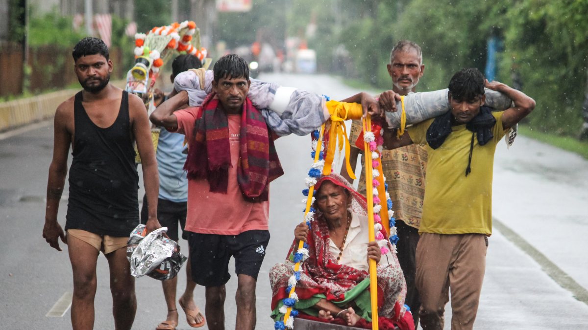 Kanwariya devotees carry elderly woman during Kanwar Yatra in Meerut