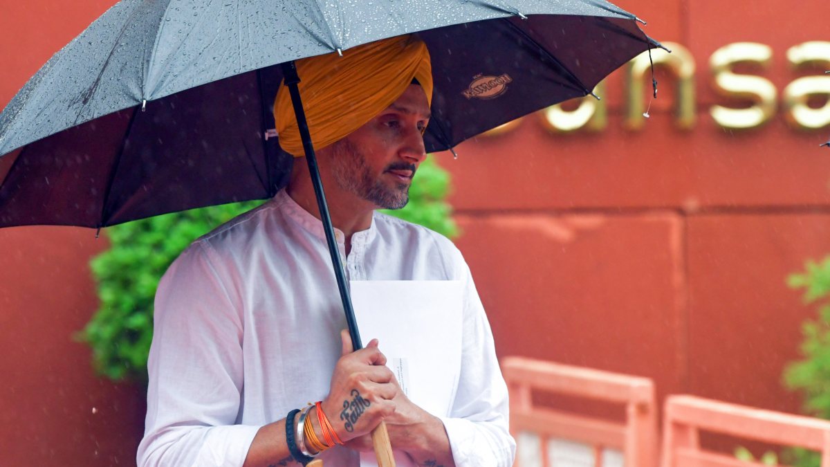 AAP MP Harbhajan Singh braves rain with umbrella at Parliament