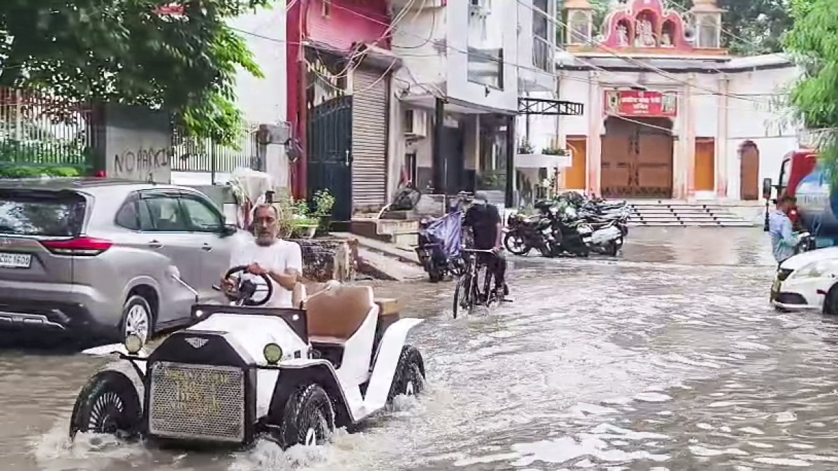 Delhi commuters wade through waterlogged street after heavy rain