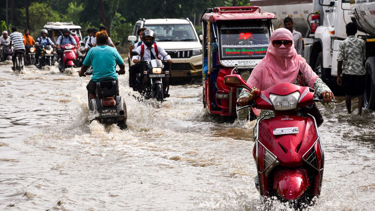 Commuters wade through waterlogged road amid heavy rain in Prayagraj