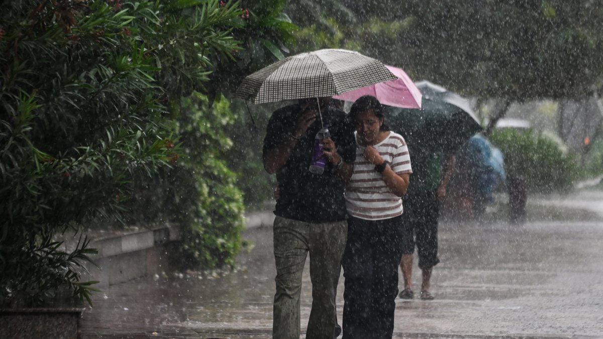 People cover themselves with umbrellas amid heavy rainfall, in New Delhi on…