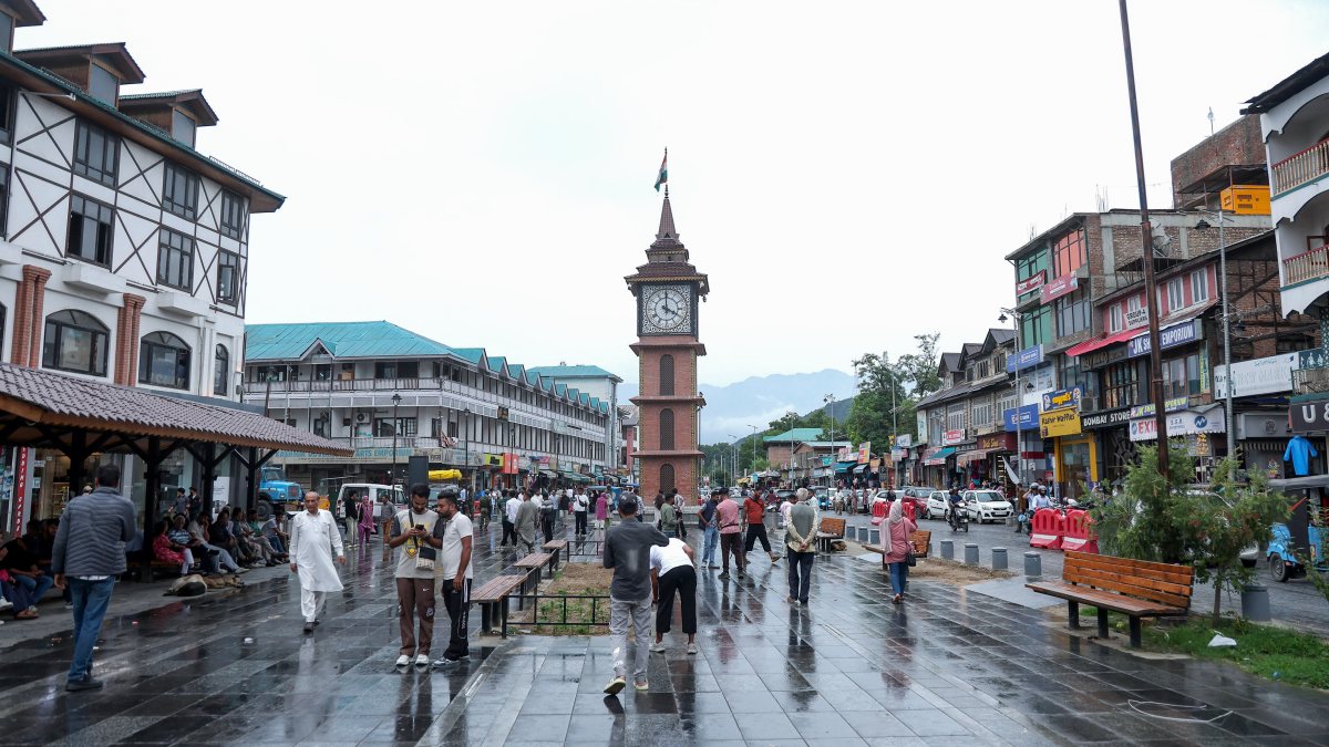 Rain sweeps Srinagar as people walk through Lal Chowk