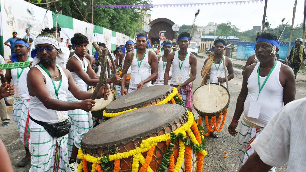Tribal men dressed in traditional Adivasi attire play traditional drums and…