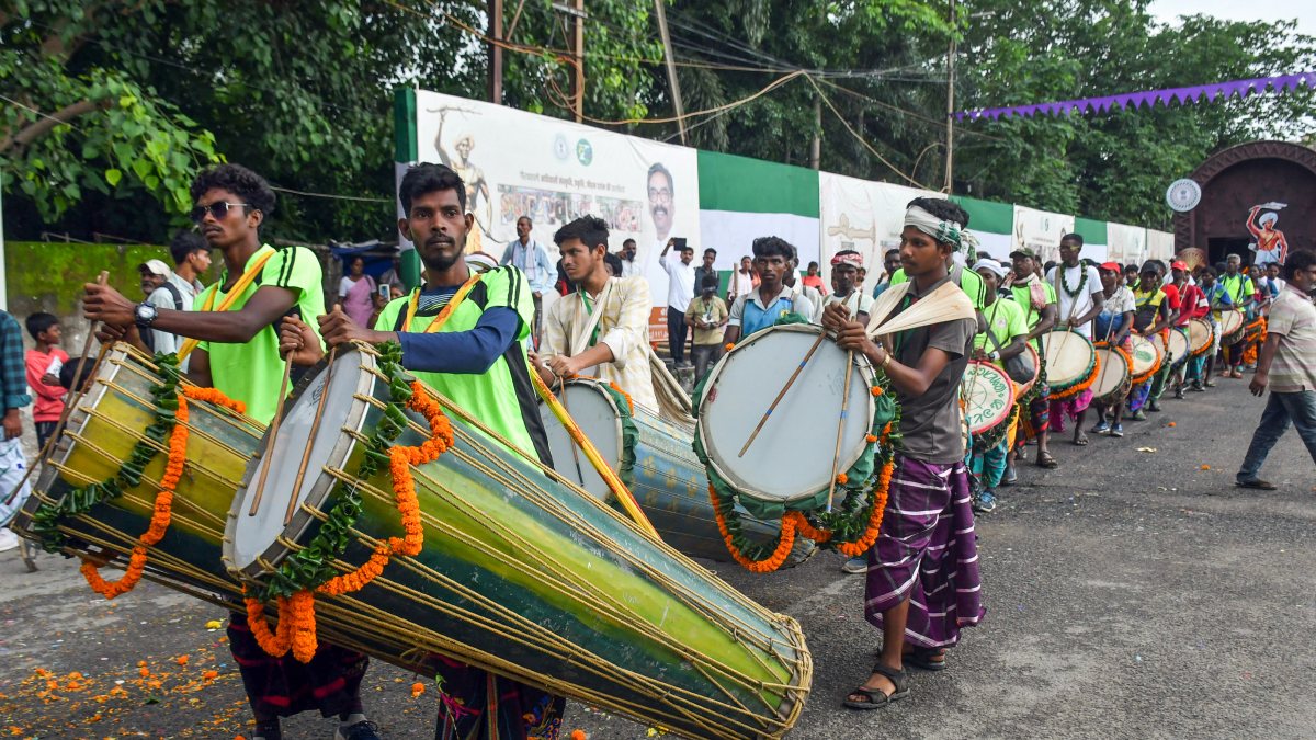 Tribal men dressed in traditional Adivasi attire play traditional drums and…