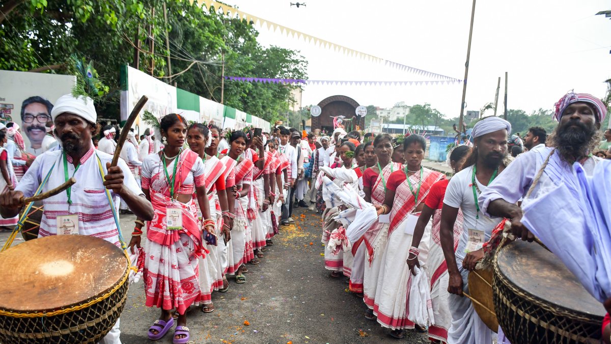 Tribal men and women dressed in traditional Adivasi attire play traditional…