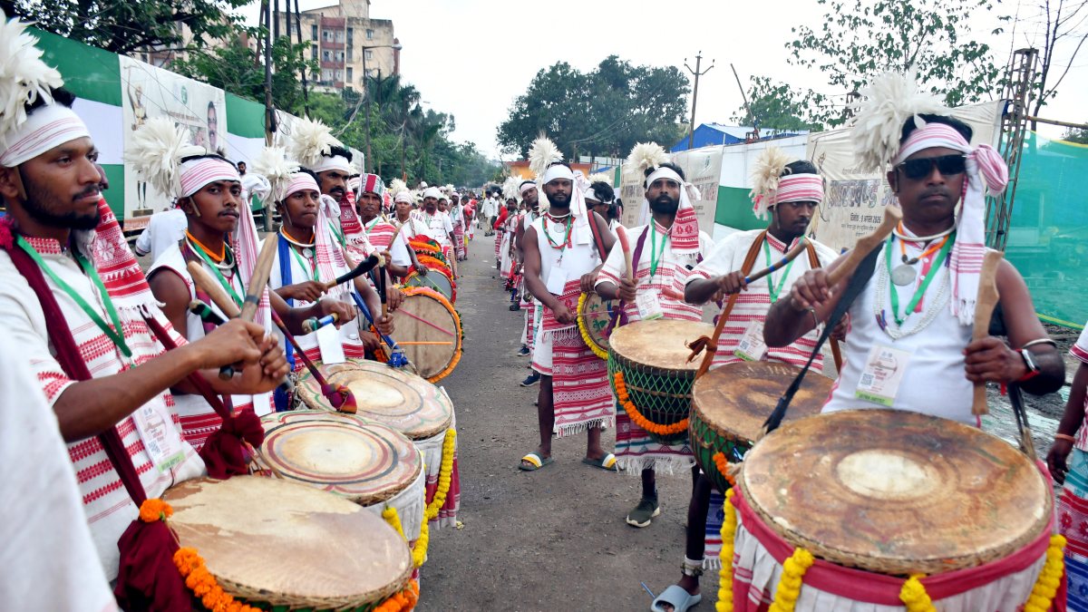 Tribal men dressed in traditional Adivasi attire play traditional drums and…