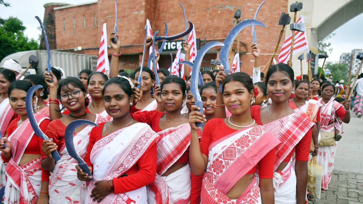 Tribal women dressed in traditional Adivasi attire play traditional drums and…