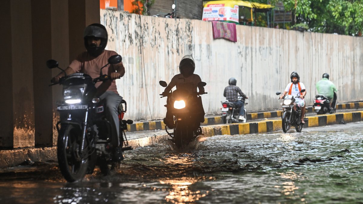 Commuters wade through waterlogged underpass in New Delhi