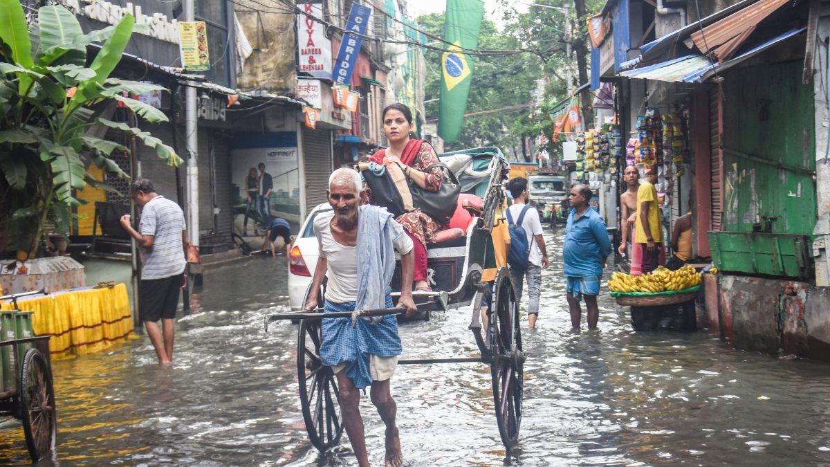 Kolkata rickshaw puller wades through waterlogged street after rain