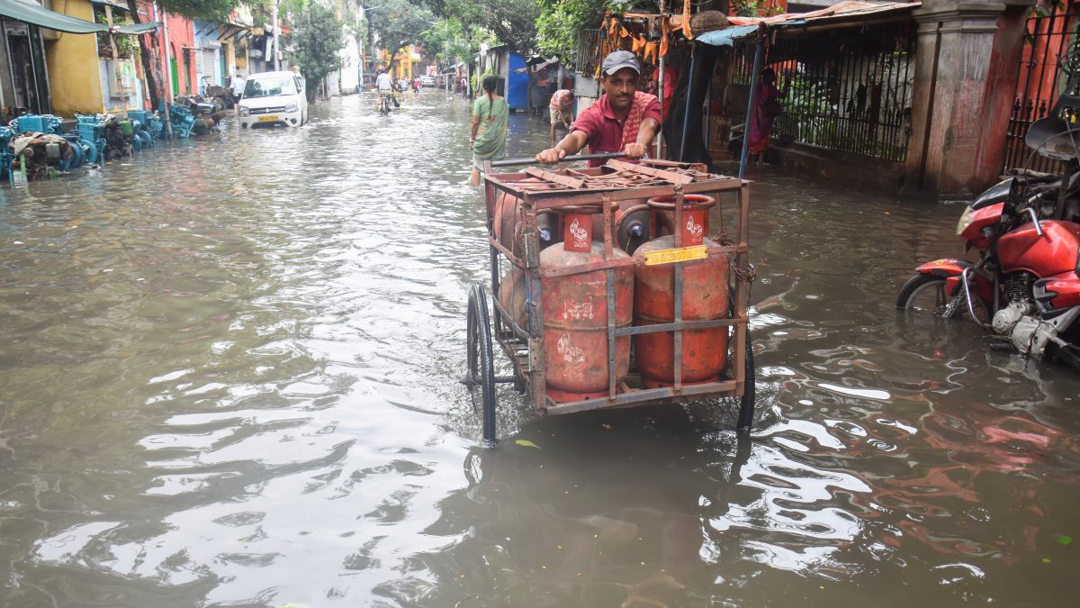 Kolkata worker moves LPG cylinders through waterlogged street
