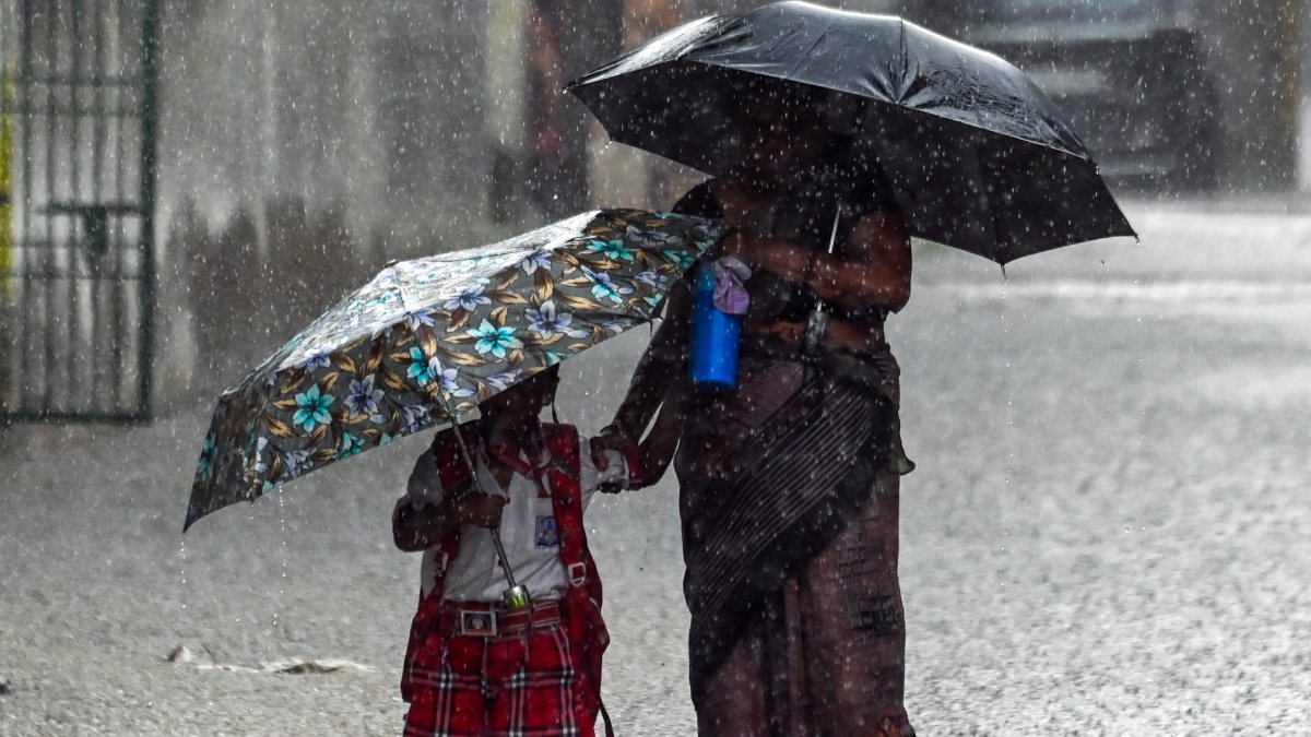 Rain lashes Ghaziabad as woman, child brave downpour with umbrellas