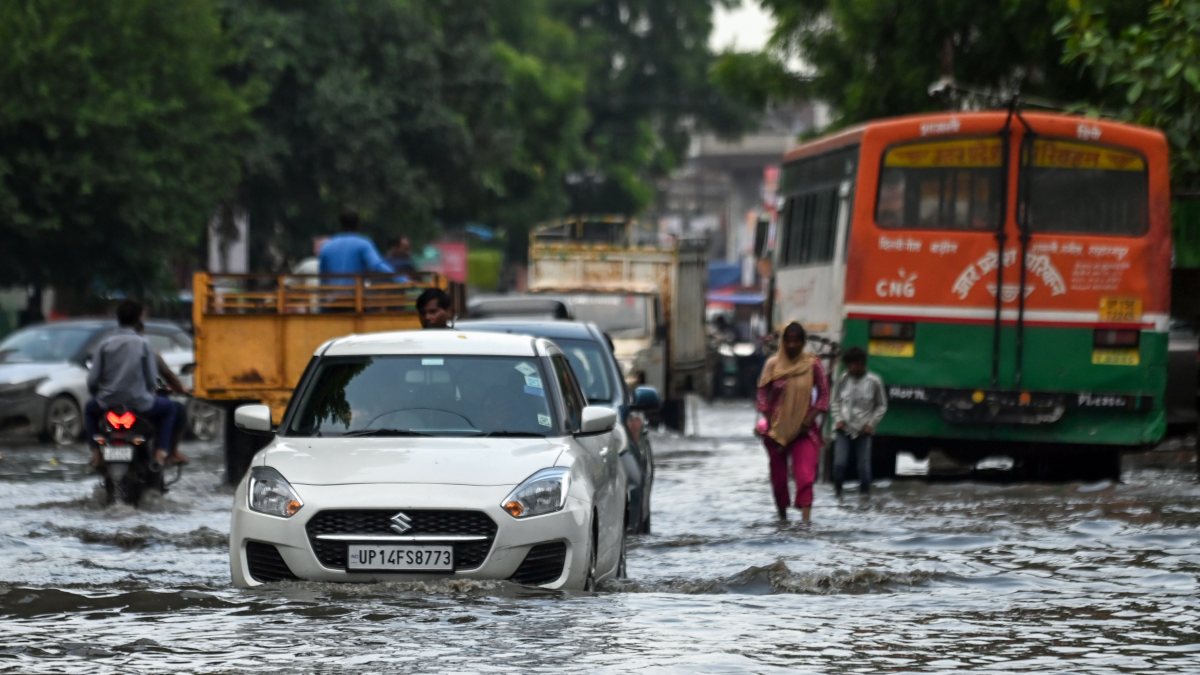 Commuters wade through waterlogged road after heavy rain in Ghaziabad