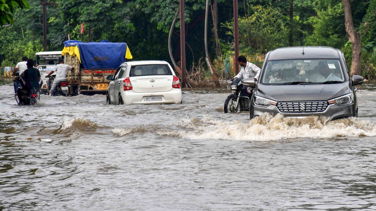 Commuters wade through waterlogged road after monsoon rain in Prayagraj