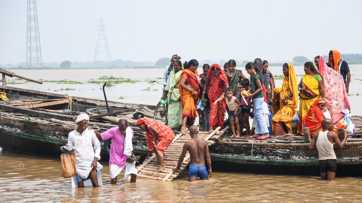 People with their belongings arrive by boat from the flood-affected Nakta…
