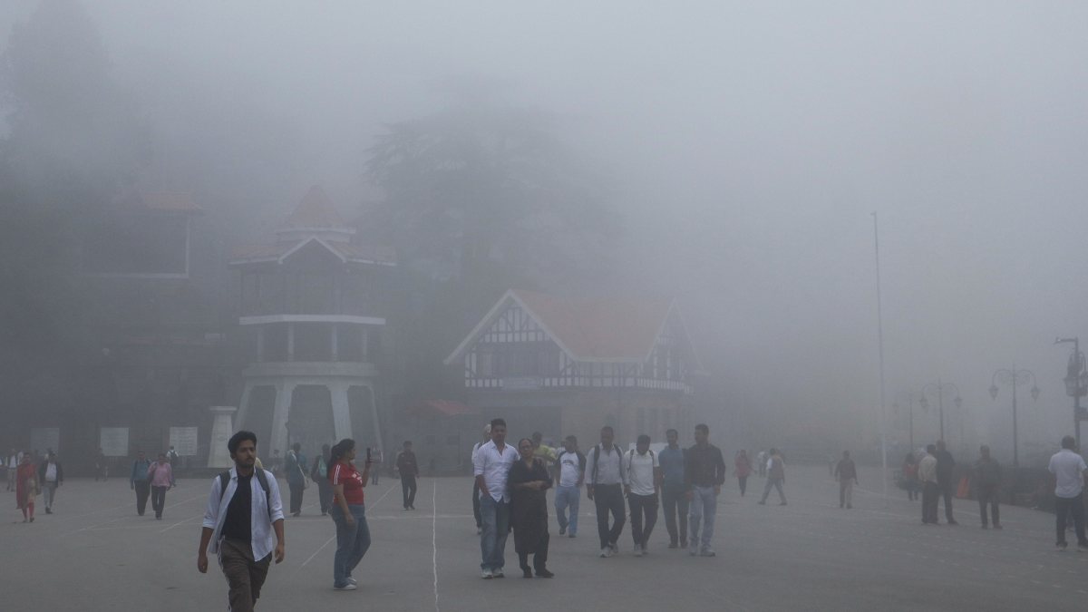 Dense fog envelops Shimla's Ridge Maidan as tourists stroll through
