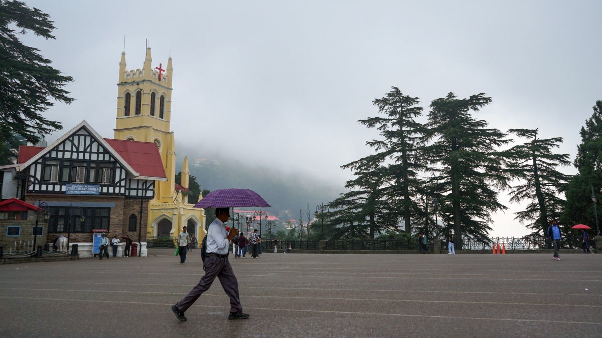 Light rain showers in Shimla as man walks with umbrella