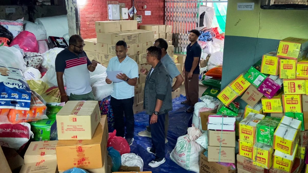 People inspect and prepare relief materials, including food supplies, cartons…
