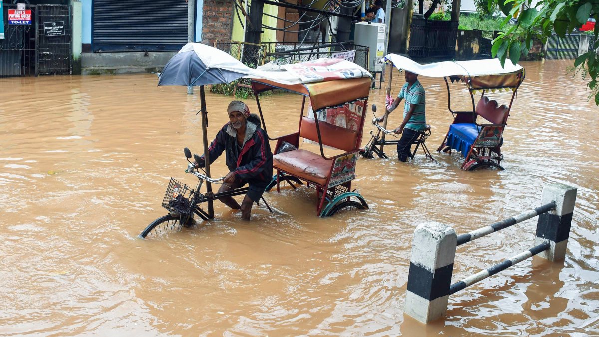 Rickshaw pullers wade through waterlogged Guwahati road after heavy rain