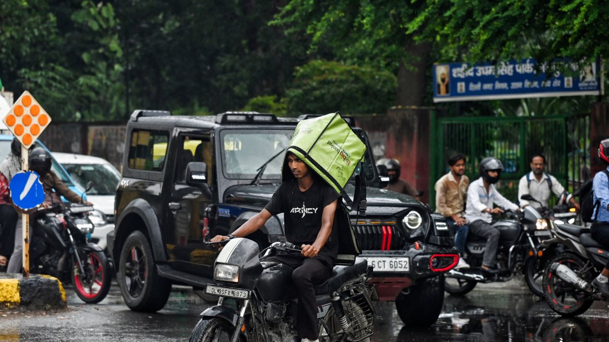 Delhi delivery agent wades through flooded street amid heavy rain