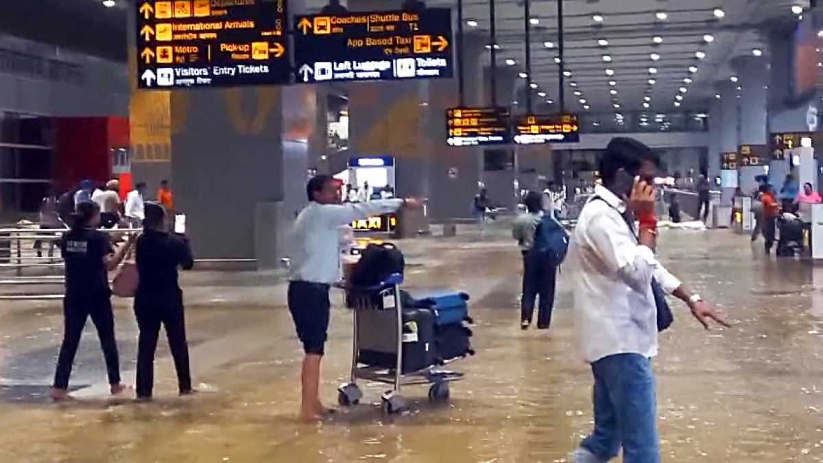 Passengers wade through waterlogged Delhi airport after heavy rain