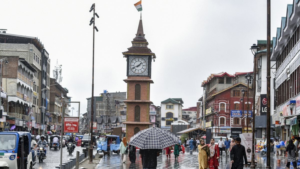 Rain lashes Srinagar as locals brave showers near clock tower