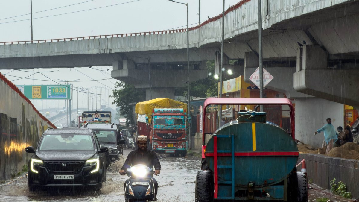 Commuters wade through waterlogged Delhi road amid heavy rain