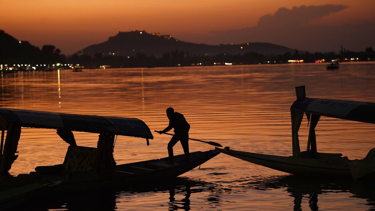 Boatman rows through Dal Lake at sunset in Srinagar