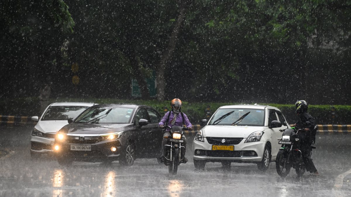Commuters wade through flooded New Delhi road amid heavy rain