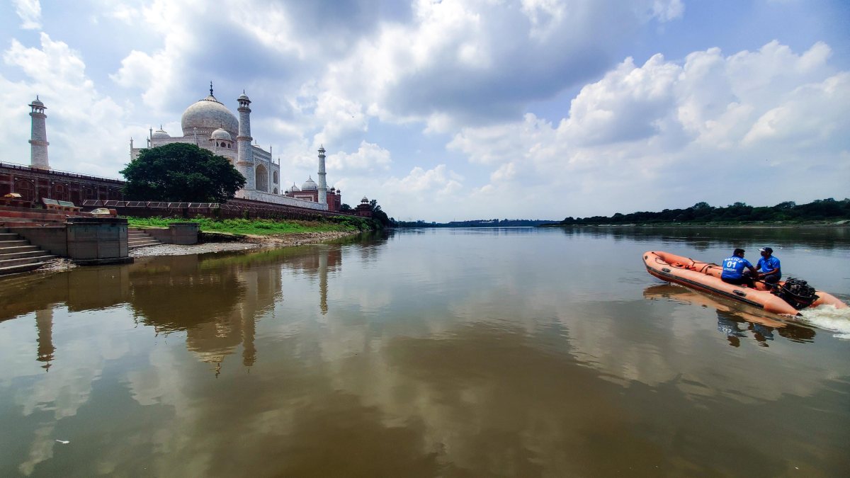 Steamer navigates Yamuna behind Taj Mahal under cloudy sky
