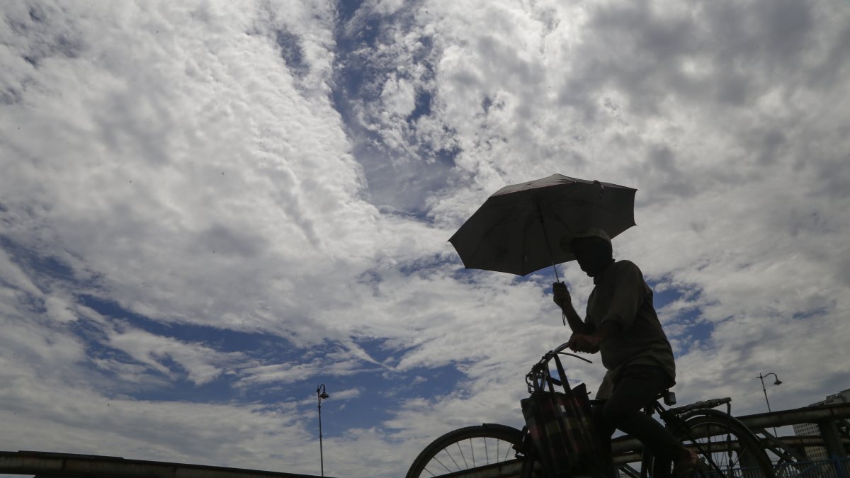 Cyclist crosses Ellis bridge on cloudy evening after rain in Ahmedabad
