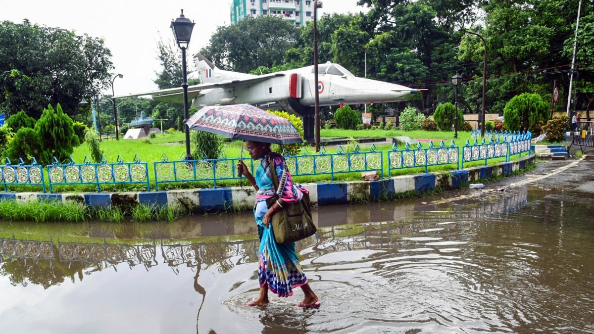 Woman walks waterlogged Kolkata street with MiG-27 in background