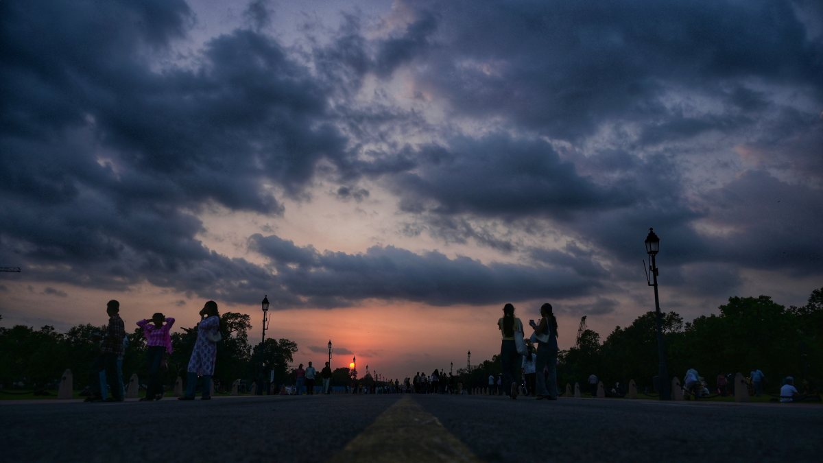 Silhouettes at Kartavya Path under cloudy sunset sky