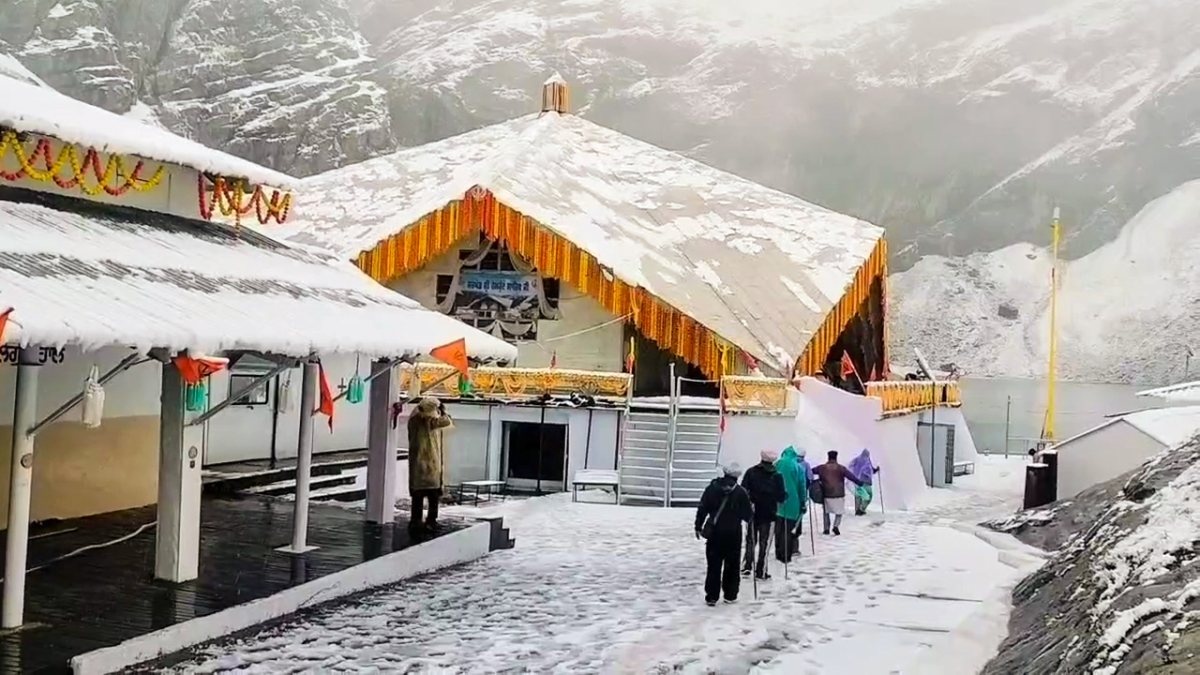 Devotees walk through snow near Hemkund Sahib in Chamoli