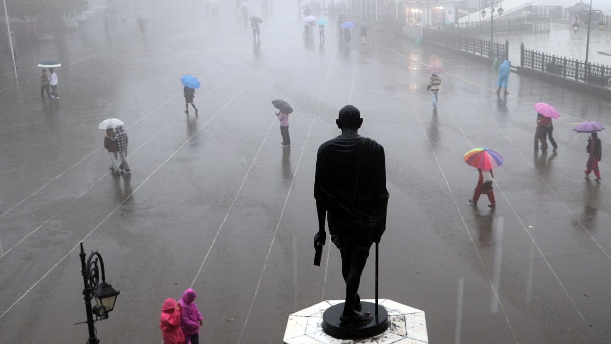 Shimla residents walk with umbrellas in heavy fog and rain