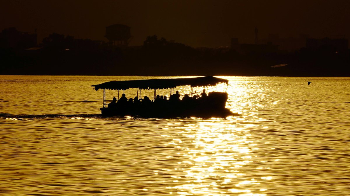 Tourists enjoy boat ride on Anasagar Lake at sunset in Ajmer