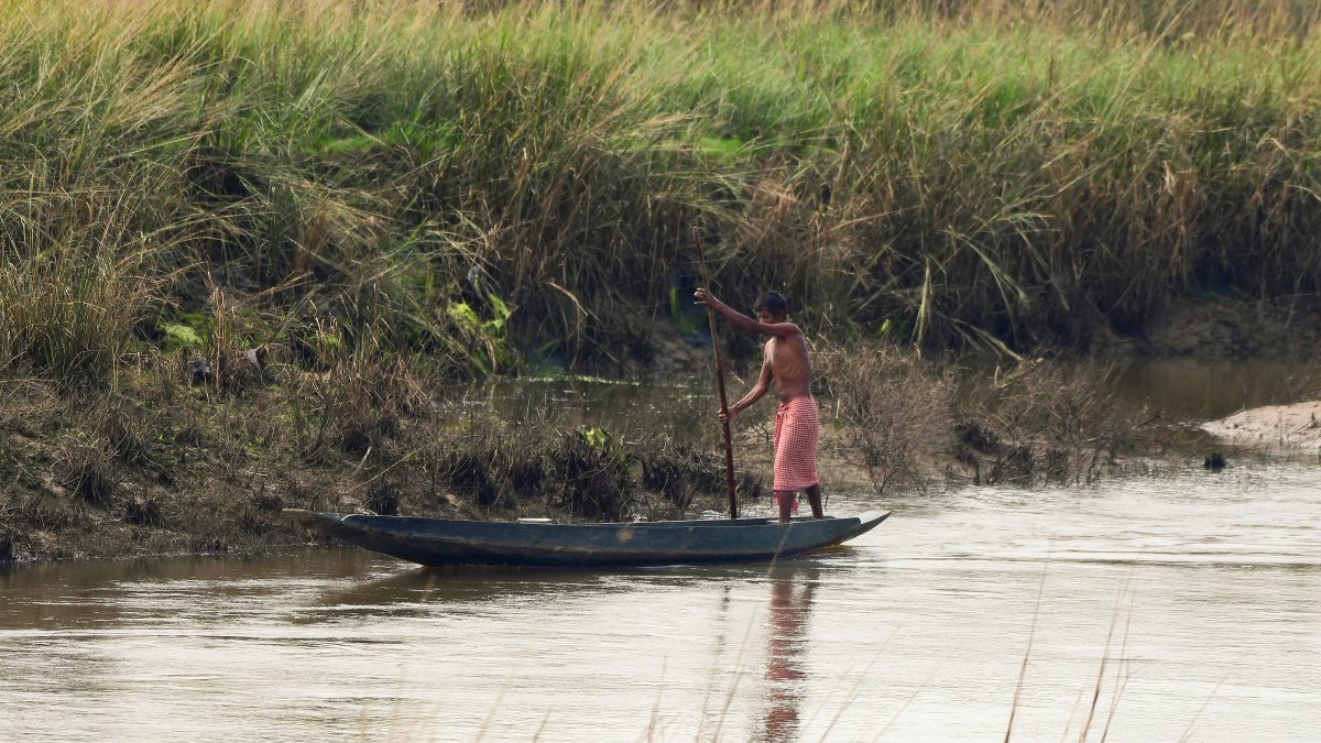 Fisherman rows boat on Haria River in Nagaon