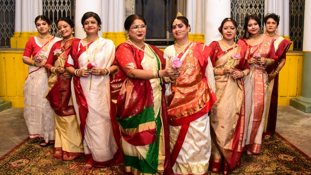Women in Bengali attire pose with lotuses ahead of Durga Puja