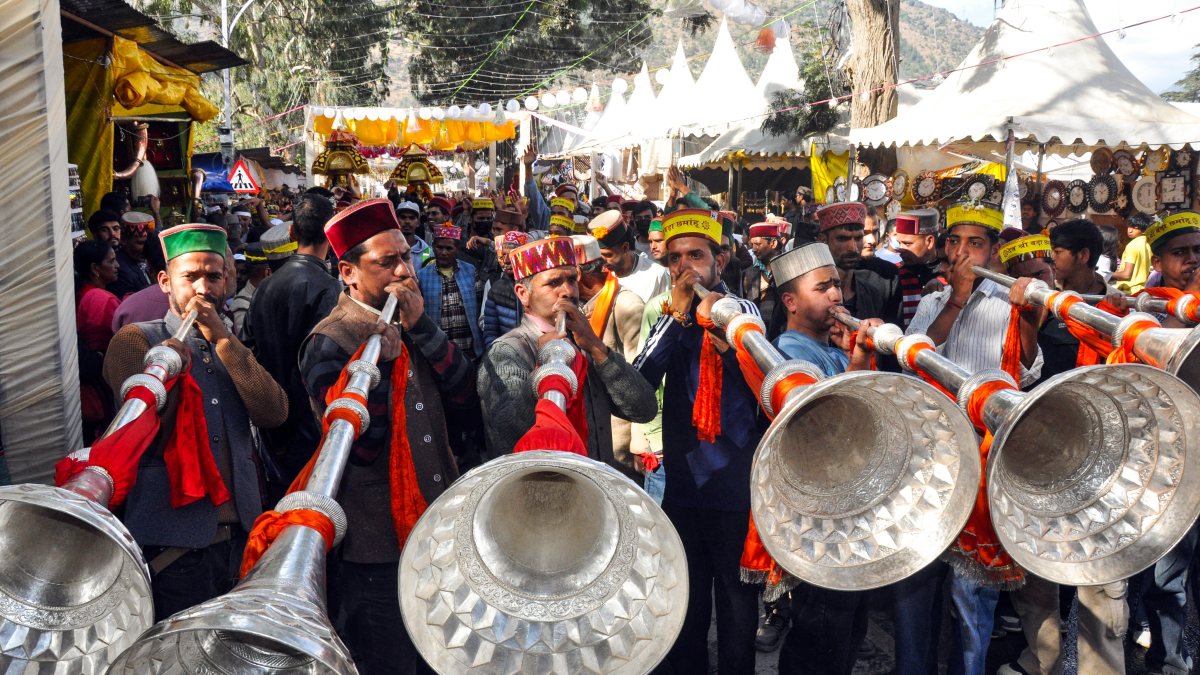 Devotees play trumpets in Kullu Dussehra procession